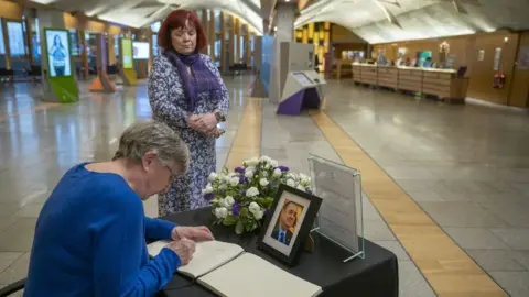 PA Media A woman signs the book of condolence for Alex Salmond in the Scottish Parliament
