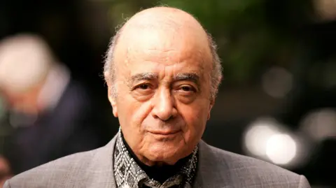 Getty Images Headshot of Al Fayed, a balding man with a wrinkled face and greying eyebrows. He is looking at the camera wearing a grey suit jacket, black patterned shirt and a black cravat.