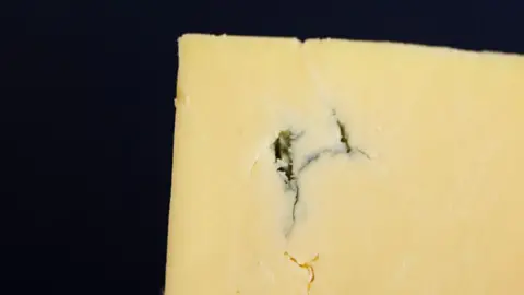 Neal's Yard Dairy Close-up of yellow cheese with a little crack in it.