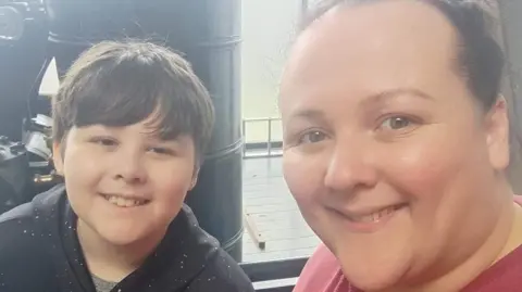 Claire Dyson Claire and Dylan are looking at the camera and smiling in this selfie. Claire is wearing a red t-shirt with her hair tied back and Dylan, who has short dark brown hair, is wearing a black hoody with white speckles on it.