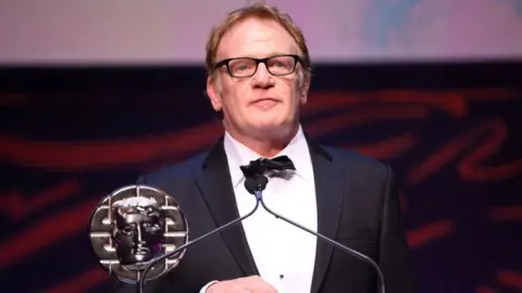 Getty Images Mark Lewis Jones accepts the Siân Phillips Award on stage during the 2024 BAFTA Cymru awards