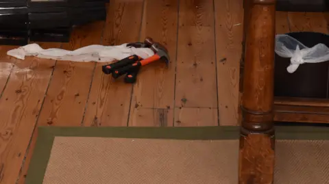 Devon and Cornwall Police/PA Wire Image shows weapons on the a wooden floor. The claw hammers have orange and black handers.