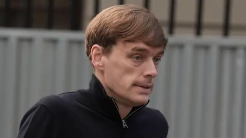 Brian Lawless/PA Wire James Lawrence arrives at High Court in Dublin. He has short blond hair and is wearing a black top with a zip collar.