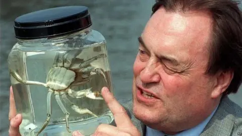 PA Media John Prescott in 1997 holding a jar with what appears to be a crab inside