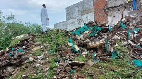 Afreen Fatima Javed Mohammad stands atop the debris, staring at where his house used to be before it was demolished in India's Uttar Pradesh state.
