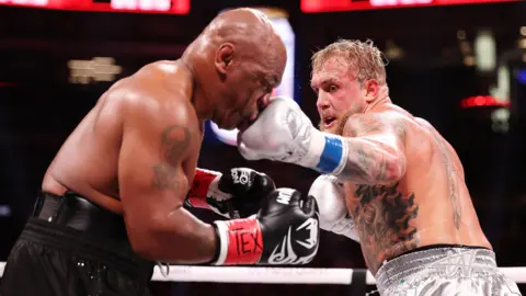 Getty Images (L-R) Mike Tyson and Jake Paul fight during LIVE On Netflix: Jake Paul vs. Mike Tyson at AT&T Stadium 
