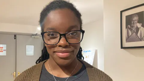 BBC Nyarai smiling at the camera. She is wearing glasses and has her hair pulled back.