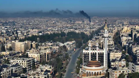 Getty Images A birds-eye picture of Aleppo with black smoke rising above the city.