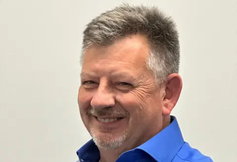 Craybeck Law Craybeck Law website photo of Ron Hiller - he is smiling, he has a full-ish head of graying hair, cut fairly short, and a moustache and goatee beard. He is wearing a cobalt-blue open neck shirt.