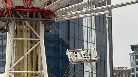 BBC A shot of the ride in daylight, showing white plastic seats at an angle with chains twisted together.