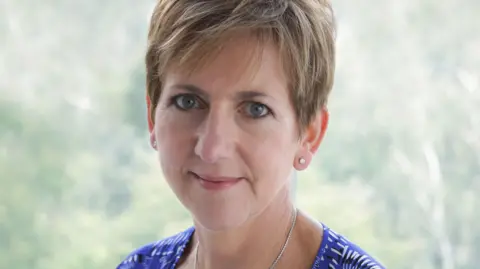 Carole Gilling-Smith Dr Carole Gilling-Smith has short light brown hair. This is a head and shoulders photo. She wears a blue and white patterned top and a silver necklace.