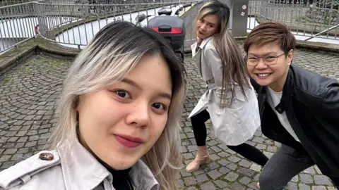 Rungtiwa Thangkanopast Rungtiwa and Phanlavee pose in the background as their daughter takes a selfie with them