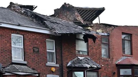 Getty Images A row of red-brick terraced houses with tiled roofs which have been badly damaged in a storm.