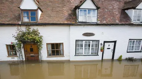 Getty Images A row of pretty old white cottages in the centre of Tewkesbury in Gloucestershire has been inundated with brown floodwater, which is almost up to the bottom of the ground floor windows.