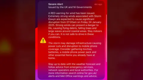 Screengrab from a mobile alert that reads "Notification centre - severe alert issued by the UK and NI governments
A red warning for wind has been issued. Extremely strong winds associated with Storm Eowyn are expected to cause significant disruption from 07:00am on Friday 24 January 2025. Strong winds can present a danger to life causing flying debris, falling trees and large waves around coastal areas. Stay indoors.