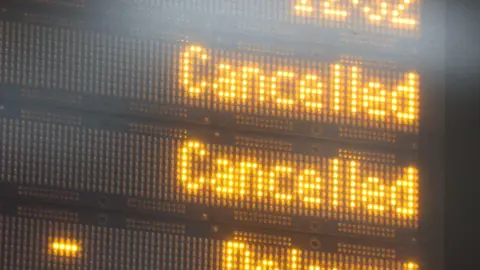 PA Media A train departure board showing a number of trains have been cancelled.