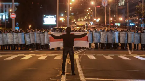 European Pressphoto Agency A protest is Belarus, August 2020. A lone man holds a white flag with a red stripe up to a crowd of riot police.