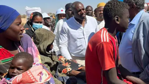 BBC David Lammy in a white amidst a crowd of Sudanese people newly arrived in Chad and aid workers.