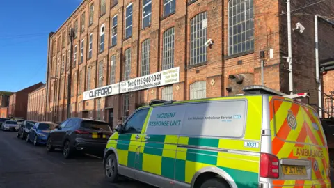 BBC An incident response unit is parked outside a large building.