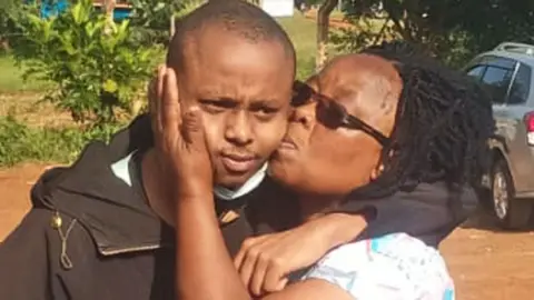 Gerald Karicha Billy Mwangi frowns slightly as he is kissed by his mother after he was freed following his abduction
