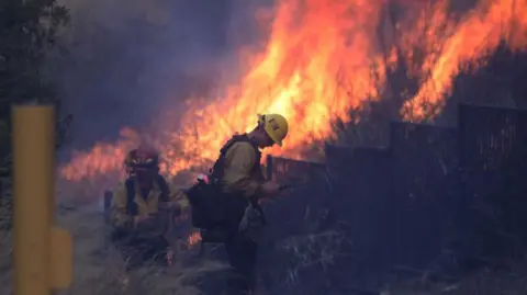 Getty Images A firefighter battles the flames as fires rage in Southern California