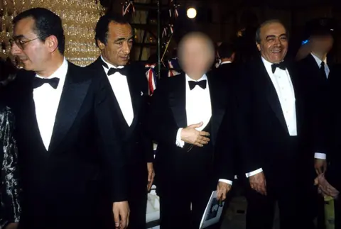 Shutterstock Ali with his brothers Salah and Mohamed (L-R). They are all dressed in black tie and Mohamed is smiling broadly at the camera.
