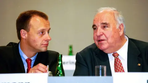 Getty Images Friedrich Merz in a blue tie on the left listens to the older Helmut Kohl talking