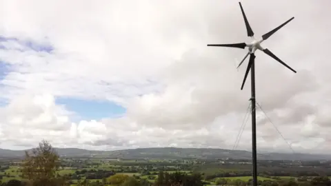 Michael Wilkinson A small, five-bladed wind turbine in Michael Wilkinson's garden which overlooks green fields and hills in the Suir Valley, County Kilkenny