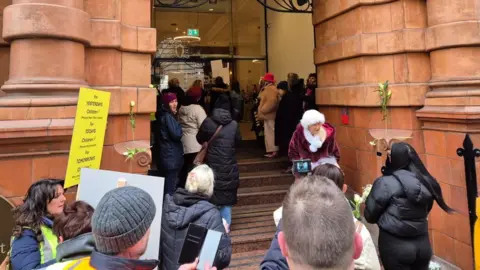 JohnLawrence Protesters gather on steps at the entrance to the Greater Manchester Combined Authority's Oxford Street office. Some can be seen close to the glass doors leading inside the headquarters.