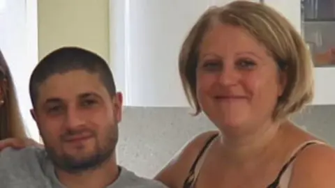 Essex Police Giuseppe Morreale, on the left of the picture, wearing a grey T-shirt. He has closely-shaved dark hair and a stubbly beard. His mother, Maria Ricotta, is on the right-hand side of the photo. She is smiling at the camera. She has blonde hair, cut into a bob, and is wearing a top with black and white straps.