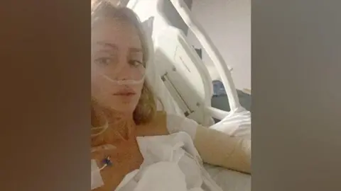 Charlene Morrisey Charlene Morrisey lies in a hospital bed. She has blonde hair. She is hooked up to various machines and wrapped in bandages.