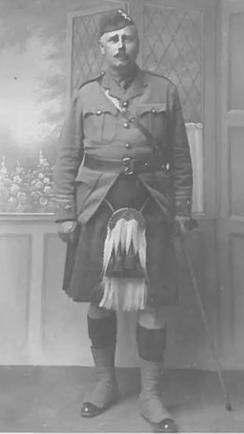 The Peoples Archive/JD Swanston family Black and white picture of JD Swanston. He is wearing a uniform including a kilt, large sporran and hat. He has a walking stick and a moustache.