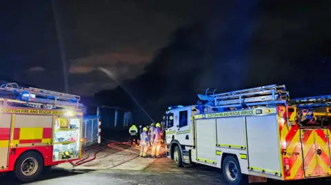 Aberdeen Harbour Tours Firefighters at scene of major blaze, two fire engines either side of crews with a jet of water going into the smoke.