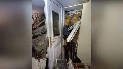 Emyr Owens A white front door completely blocked by rubble which has also swept into the home as a result of Storm Bert