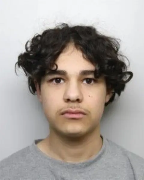 West Yorkshire Police A mugshot of Bardia Shojaeifard. He has curly black hair and is wearing a grey jumper. 