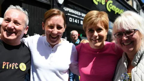 Getty Images From left to right - Alan Black with silver hair and a black shirt reading PT FC, Mhairi Black in a white top, Nicola Sturgeon in a pink top and Mhairi Black's mother, who has blond hair, a grey coat and an SNP pin badge
