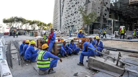 Getty Images Migrant builders take a break while working at a construction site by the Corniche, in Doha, on November 24, 2022, during the Qatar 2022 World Cup football tournament.