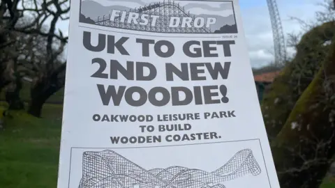 The front cover of the magazine First Drop published at the time when Megafobia was being built. The headline reads 'UK to get 2nd new woodie! Oakwood leisure park to build wooden rollercoaster'. Below is a black and white sketch of Megafobia.