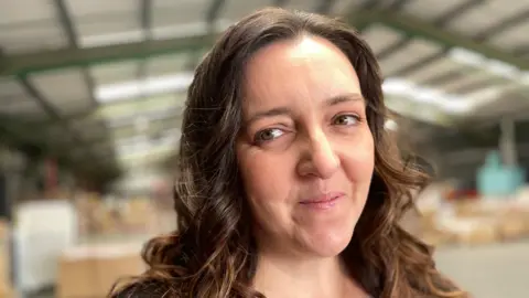 Marie Gregory - a head and shoulders hot of a woman with long, dark, curly hair.