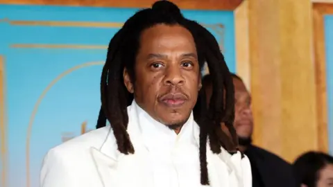 Getty Images Jay-Z is photographed at a movie premier wearing a white suit