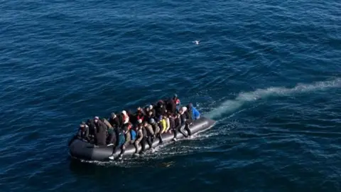 EPA Migrants wearing coats and jackets seen packed onto a black inflatable boat on the English Channel
