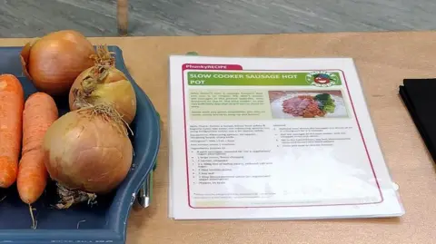London Borough of Sutton A recipe for sausage hot pot sits next to some carrots and onions