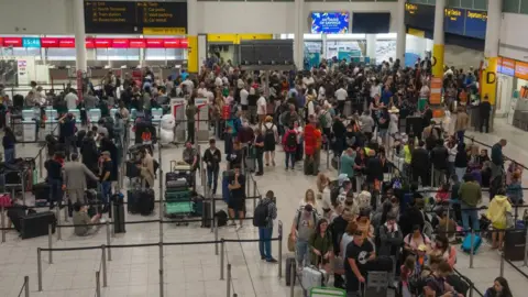 Getty Images People wait near check-in desks at Gatwick Airport