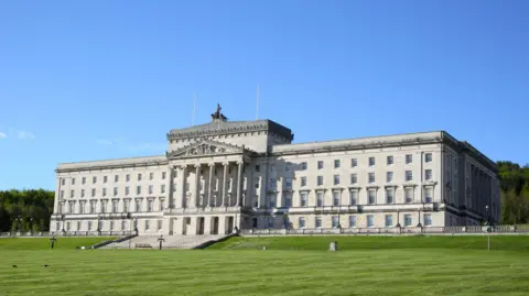 Getty Images Parliament Buildings at Stormont in east Belfast, with grass in front and blue sky above.