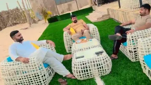 TikTok/Fadi Gujjar Fadi Gujjar with Sufian Ali and Atif Shahzad. They are sitting at a beach restaurant.