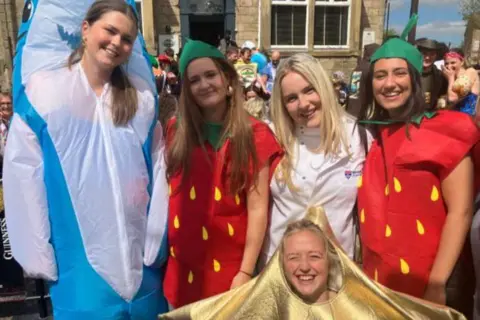 BBC/Grace Wood A group of young women in fancy dress standing outside a pub, one is dressed as a dolphin, others as strawberries