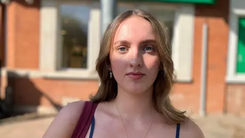 BBC/Elizabeth Baines A student in the Leeds suburb of Headingley. She has brown hair and a red brick building is blurred behind her.