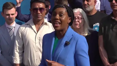 PA Kemi Badenoch wearing a blue suit surrounded by supporters
