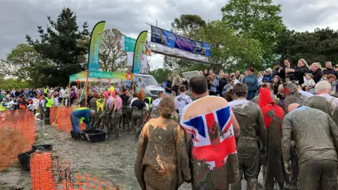 Chris Radburn/BBC Hundreds of muddy racers queue for an outdoor shower