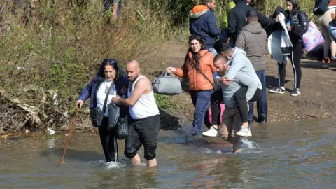 EPA File photo showing Syrian Alawites fleeing sectarian attacks in Syria's coastal region crossing the Kabir river on the border between Syria and Lebanon, in village of Haker al-Dahri, northern Lebanon (11 March 2025)